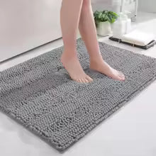 Person standing on a gray bath mat in a bathroom setting.